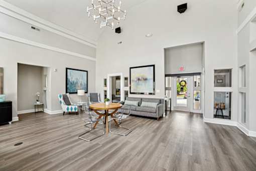 A living room with a grey couch, a wooden table and chairs, and a chandelier at Beacon Ridge Apartments, PRG Real Estate Management, Greenville, 29615