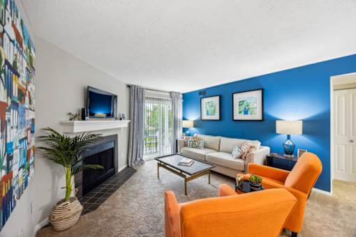 A living room with a fireplace, a couch, a chair, and a television at Chinoe Creek Apartments, Lexington, KY