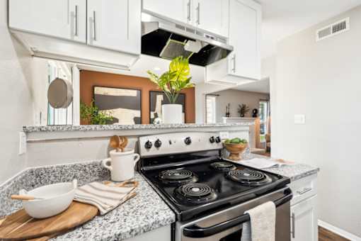 A modern kitchen with a stove top oven and a cutting board with a bowl and utensils on it. at Woodcreek Apartments, Cary, North Carolina