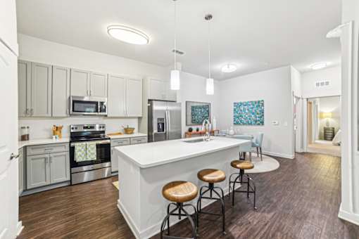 A kitchen with a white island and stools at Proximity Apartments, South Carolina, 29414