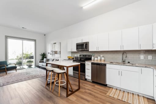a kitchen with white cabinetry and a wooden island with three stools  at The Point on 38th, Norfolk, VA