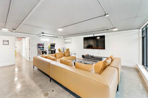 A living room with a tan couch and a television mounted on the wall at The Box, Richmond, VA, 23224