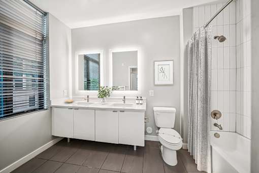 A white bathroom with a toilet, sink, and shower. at The Locks Tower, Richmond, Virginia