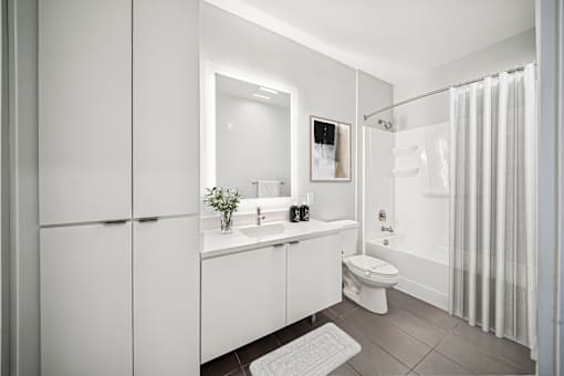 A white bathroom with a toilet, sink, and shower. at The Locks Tower, Virginia, 23219