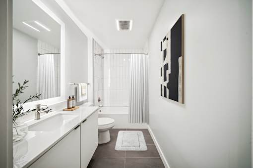 A bathroom with a white sink, toilet, and bathtub with a grey floor and a white wall. at The Locks Tower, Richmond, 23219