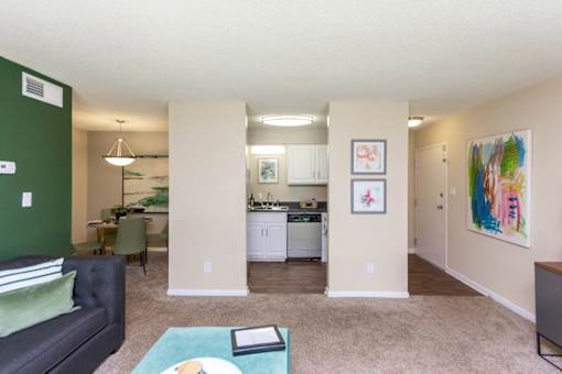 A living room with a couch, a table, and a kitchen area in the background at Clarion Crossing Apartments, PRG Real Estate Management, Raleigh