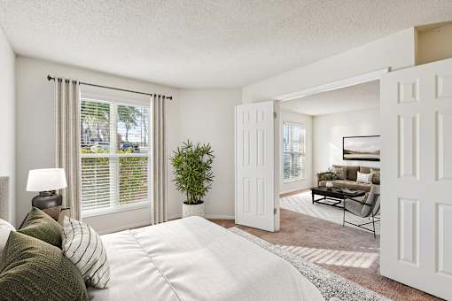 A living room with a white couch and a large window with blinds at The Falls Apartments in Raleigh NC