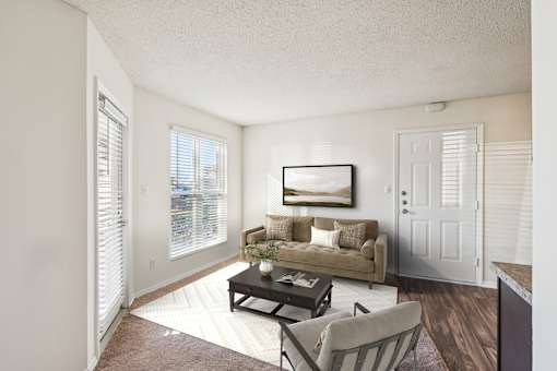 A living room with a couch, chair, and coffee table at The Falls Apartments in Raleigh NC
