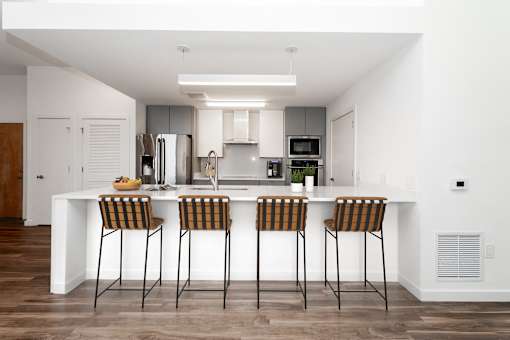 A modern kitchen with a white island and bar stools.