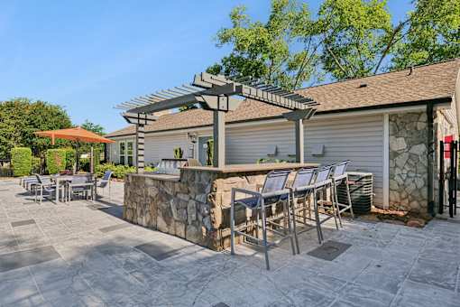 A patio with a table and chairs is in front of a house.