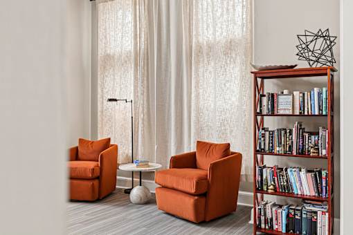 A living room with a bookshelf, two chairs, and a table.
