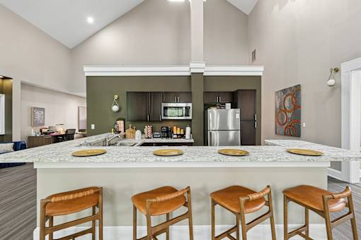 A kitchen with a marble countertop and wooden bar stools.