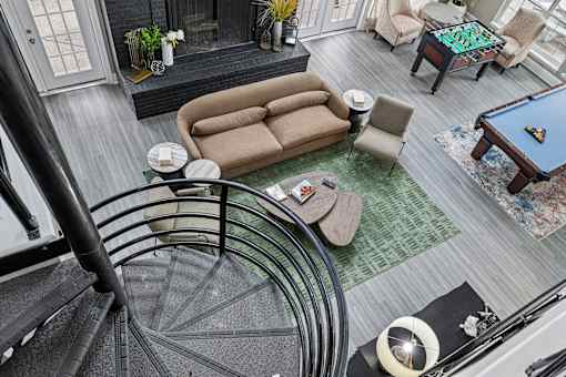A living room with a pool table and a spiral staircase.