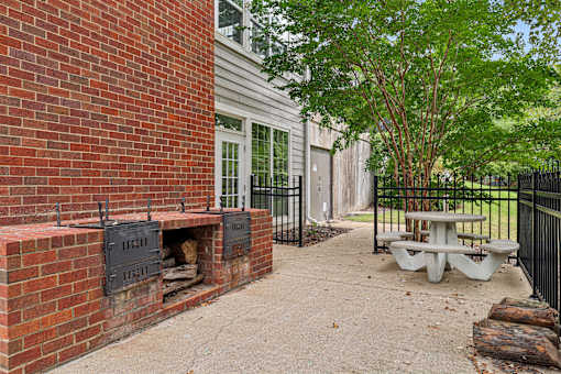 A brick wall with a fireplace and a tree in front of a house.