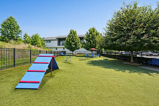 A playground with a blue slide and a red umbrella.