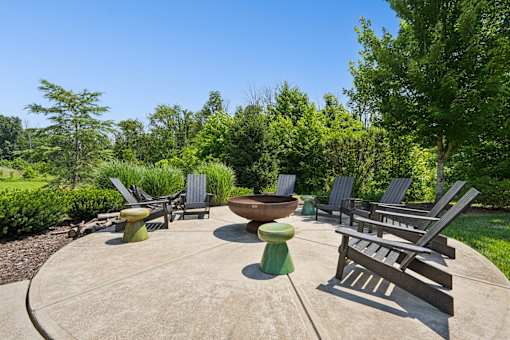 A concrete patio with a fire pit and chairs.
