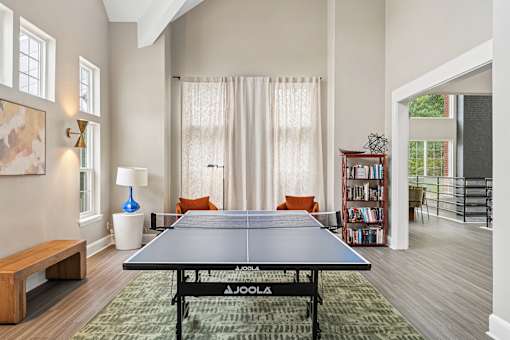 A JOOLA table tennis table in a room with a sofa and a bookshelf.