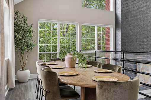 A dining room with a table set for six with a view of trees outside.