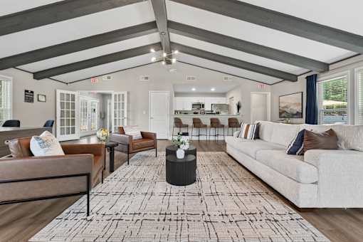 A spacious living room with a large rug and multiple seating options.