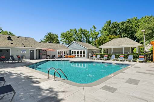 A swimming pool surrounded by a patio with chairs and a gazebo.