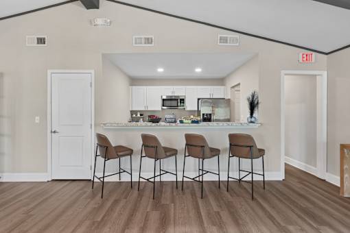 A kitchen with a bar and chairs.