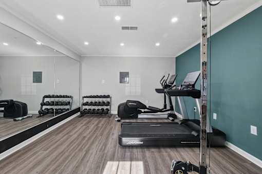 A gym with a variety of equipment including treadmills, weights, and exercise machines.