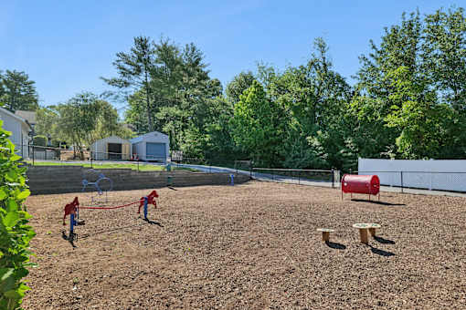 A baseball field with a red barrel and a fence in the background.