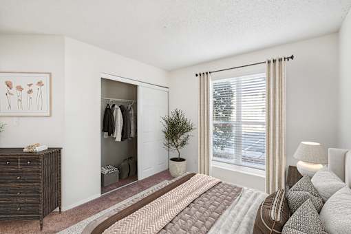 A bedroom with a bed, dresser, and window at The Falls Apartments in Raleigh NC