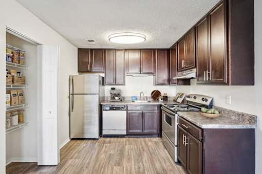 A kitchen with dark wood cabinets and stainless steel appliances at The Falls Apartments in Raleigh NC