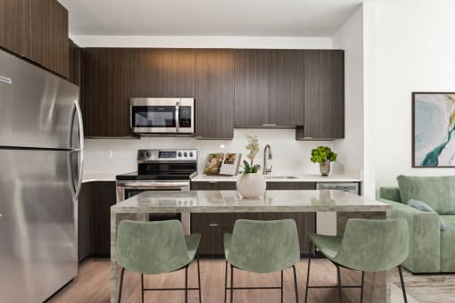 a kitchen with a large island with a marble countertop and four green chairs