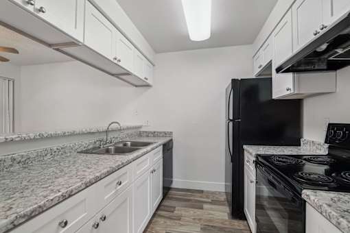 A kitchen with a black refrigerator and white cabinets.