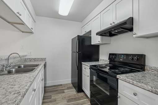 A kitchen with black appliances and white cabinets.
