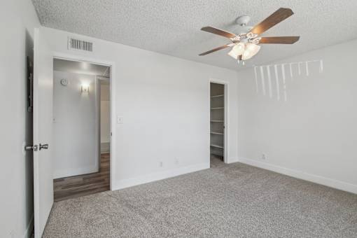 A room with a ceiling fan and carpeted floor.
