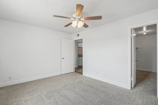 A room with a ceiling fan and carpeted floor.