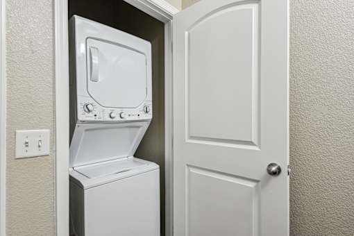 A white dryer is in a small space next to a door.