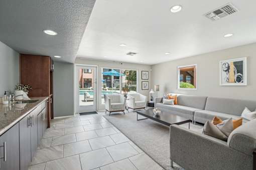 A modern living room with a grey couch and a kitchen area with a sink.