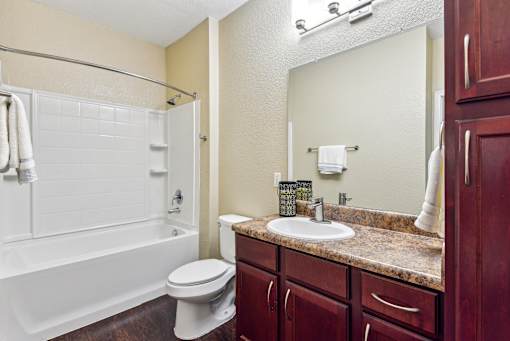 A white toilet sits next to a white bathtub in a bathroom at Overlook at Stone Oak Park Apartments, San Antonio
