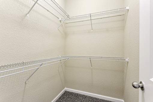A white closet with a door and a carpeted floor at Overlook at Stone Oak Park Apartments, San Antonio