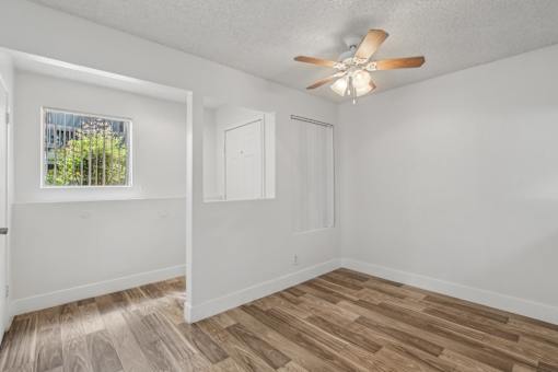 A room with a ceiling fan and wooden flooring.
