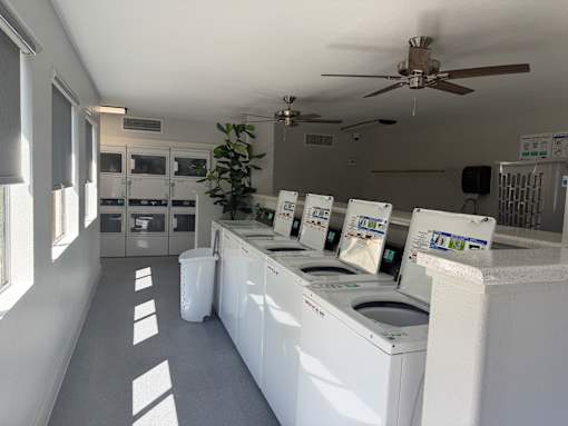 A laundromat with washers and dryers lined up.