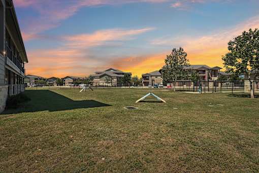 A sunset view of a park with a playground and houses in the background.