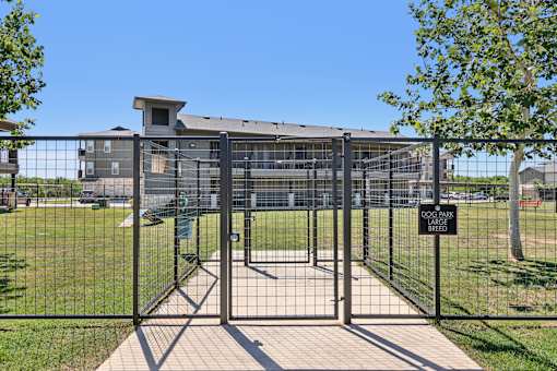 A black metal gate with a sign that reads "DOG PARK BREAK" in front of a building.