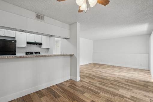 A kitchen with white cabinets and a black fridge.