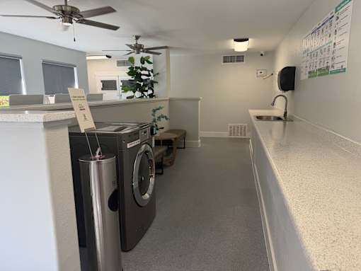 A laundry room with a washer and dryer, a fan, and a sink.