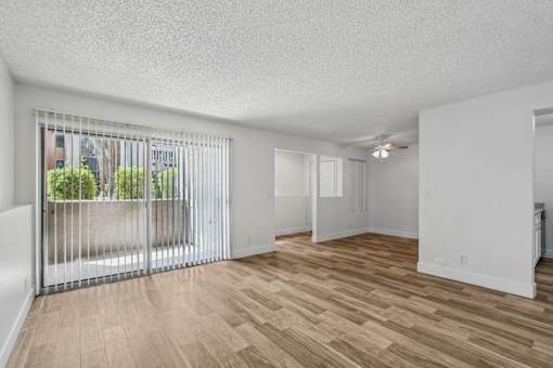 A room with a sliding glass door and wooden flooring.