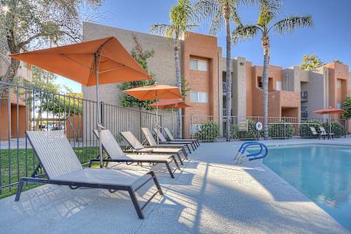 A poolside area with sun loungers and umbrellas.