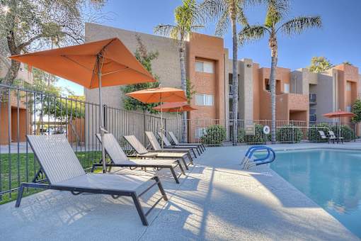 A poolside area with sun loungers and umbrellas.