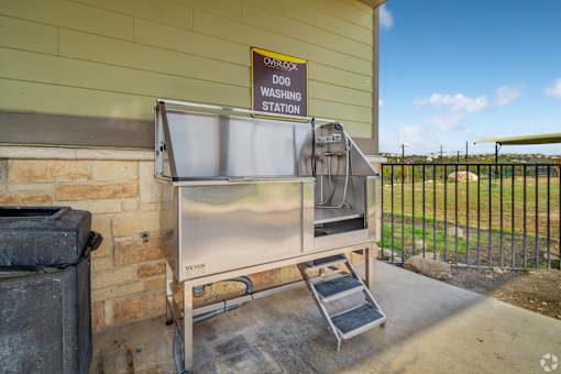 A dog washing station is located outside a building at Overlook at Stone Oak Park Apartments, San Antonio