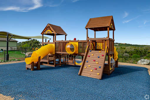 A playground with a yellow slide and a wooden structure at Overlook at Stone Oak Park Apartments, San Antonio