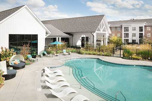 a swimming pool with white lounge chairs and a building in the background